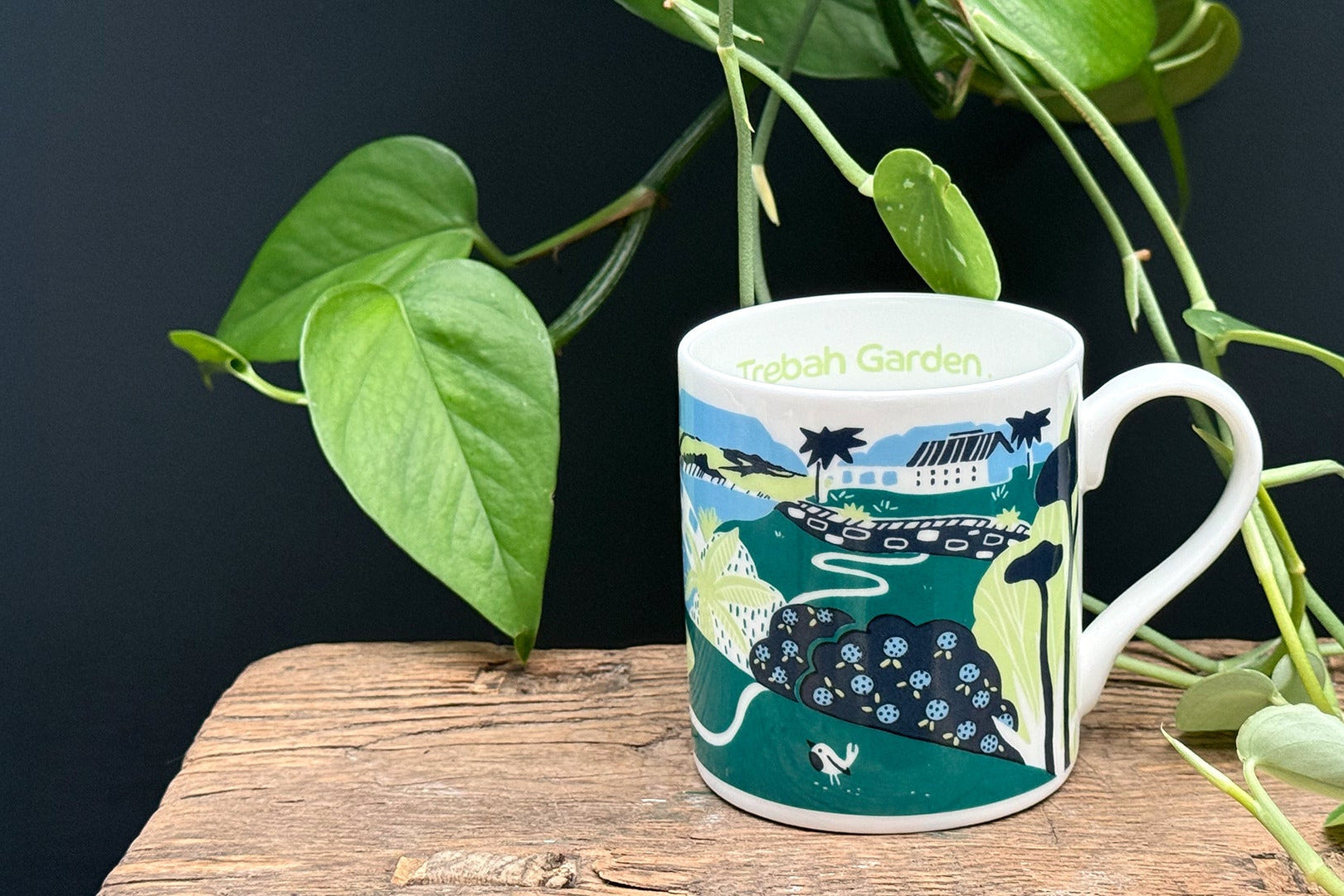 Mug with a scenic design on a wooden surface with plants
